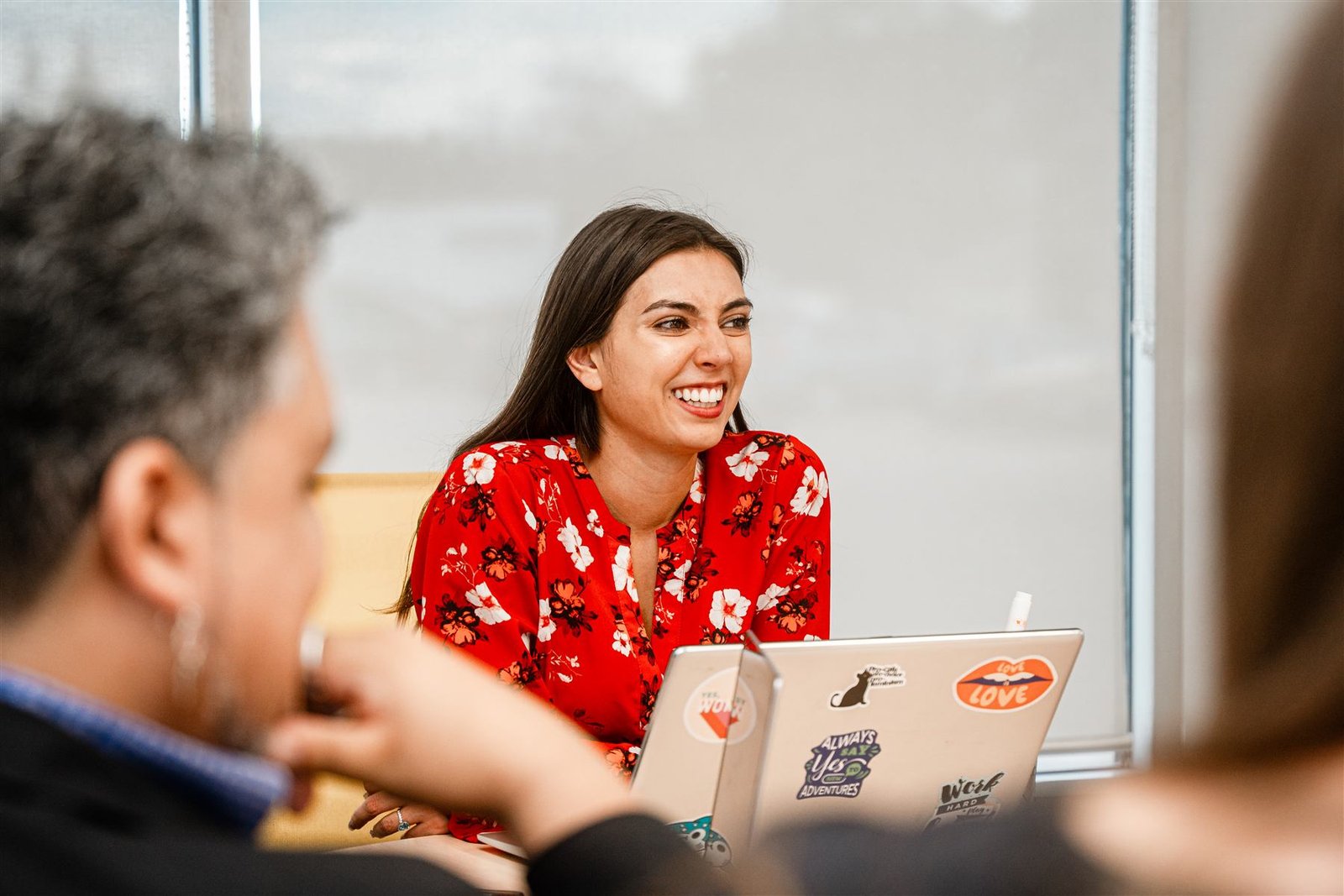 A Social Launch Labs coach laughing mid-conversation with workshop participants gathered around a laptop